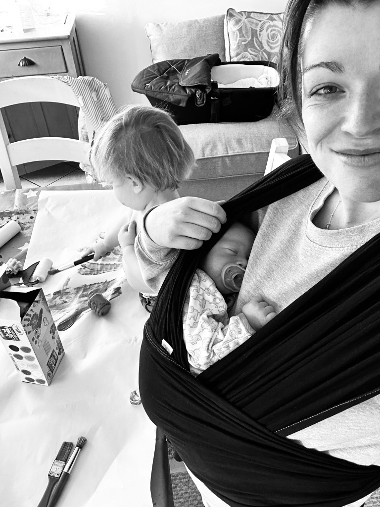 Baby-led postnatal support Bath - Norland Nanny caring for newborn while sibling plays
